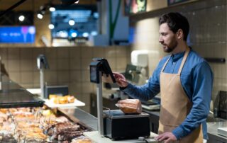 Butcher working in grocery store using digital scales to weigh deli meats
