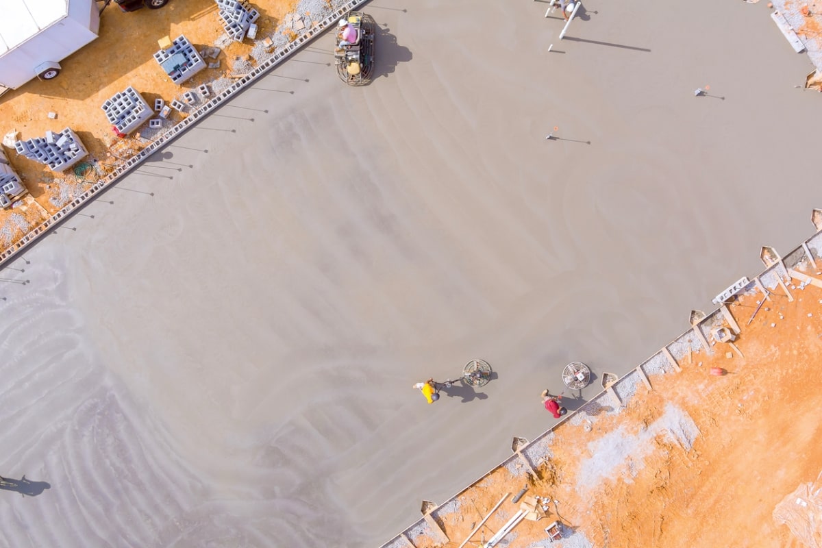 After concrete has been poured, mason works to polish concrete using concrete polishing machines.