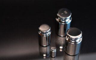 Close-up of weights used for scale calibration on a black background.
