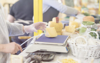 seller weighing fresh cheese on scale at farmers market