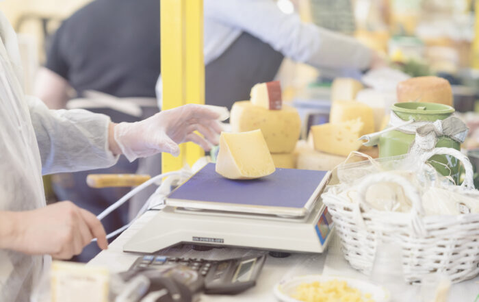 seller weighing fresh cheese on scale at farmers market