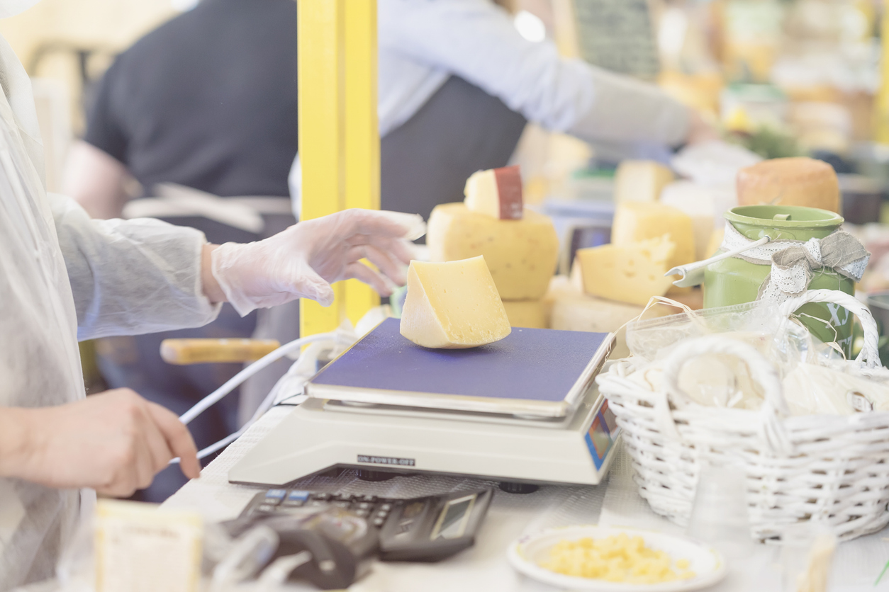 seller weighing fresh cheese on scale at farmers market